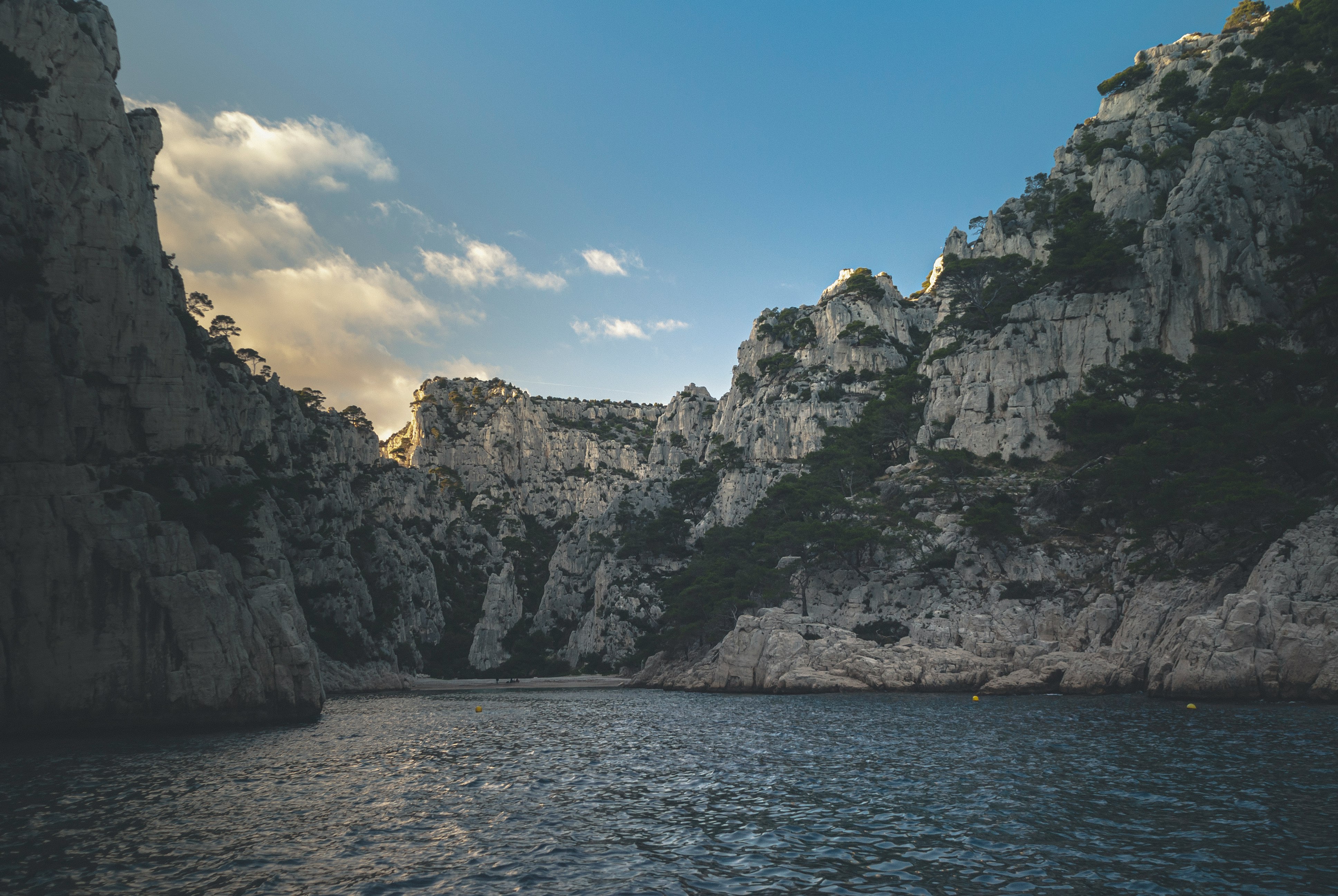 gray rocky mountain beside blue sea under blue sky during daytime